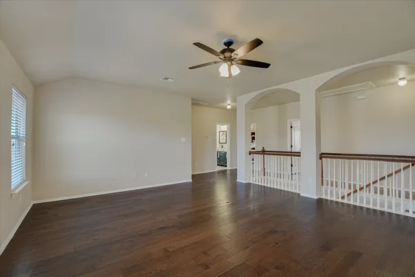 a view of an empty room with wooden floor and a window