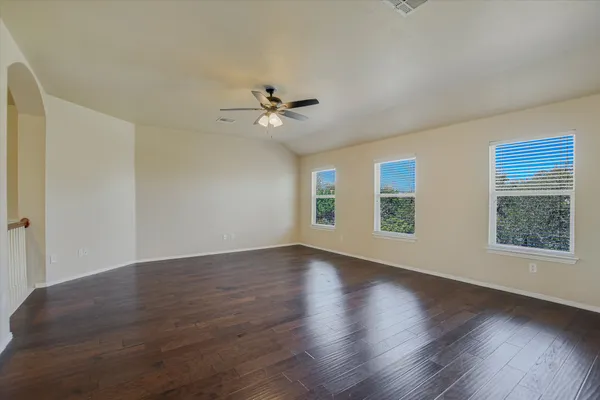a view of an empty room with a window and wooden floor