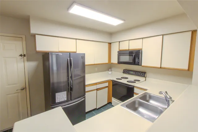 a kitchen with stainless steel appliances granite countertop a refrigerator a stove and a sink with wooden floor