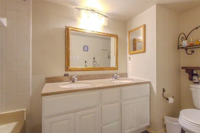 a bathroom with a granite countertop sink mirror and toilet