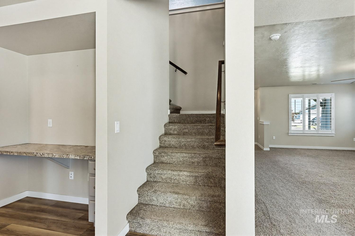 846 North Hidden View Way Star, ID 83669 - Photo 25 of 49 Carpeted staircase with dark wood-finish handrail, complemented by an integrated desk nook featuring a stone-finish countertop and wood-finish flooring