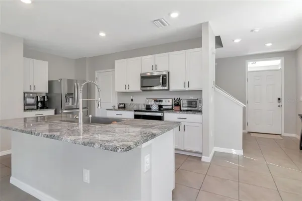 a kitchen with kitchen island granite countertop a stove sink and microwave