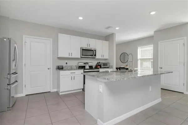 a kitchen with stainless steel appliances granite countertop a refrigerator sink and white cabinets