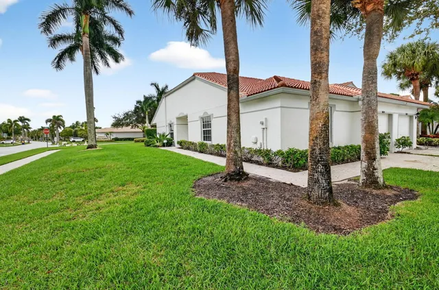 a front view of a house with yard and palm tree