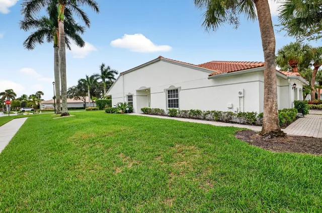 a view of a house with a yard and palm trees