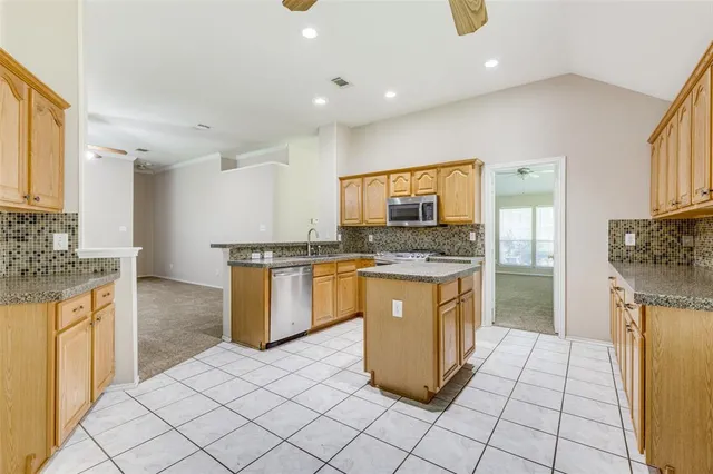 a kitchen with granite countertop a stove a sink and a refrigerator