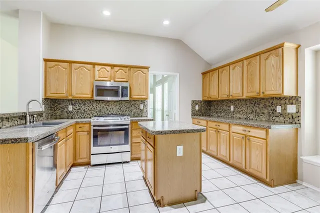 a kitchen with stainless steel appliances granite countertop a stove a sink and a microwave