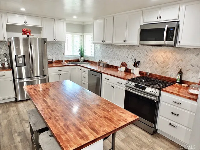 a kitchen with stainless steel appliances granite countertop a refrigerator stove top oven and sink