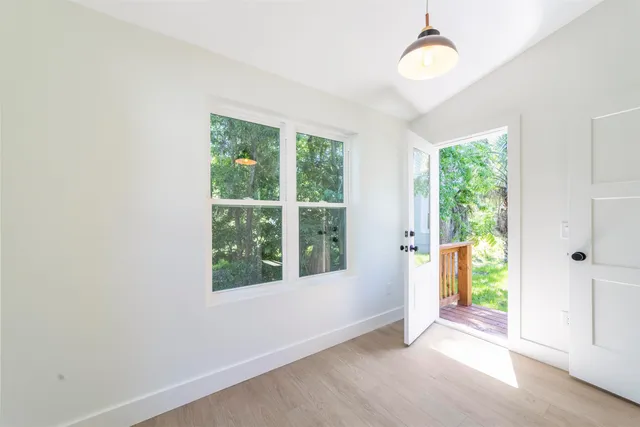 a view of an empty room with wooden floor and windows