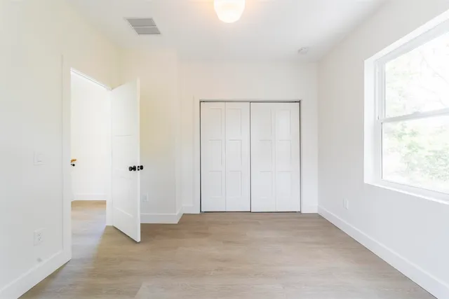 an empty room with windows and closet