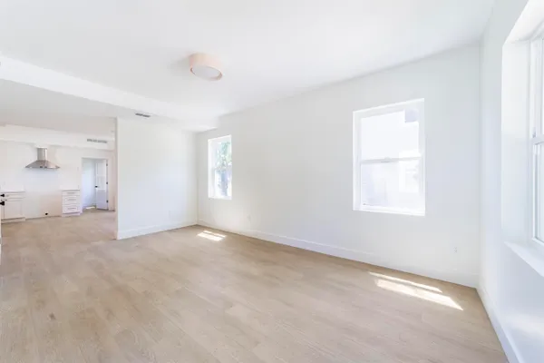a view of an empty room with wooden floor and windows