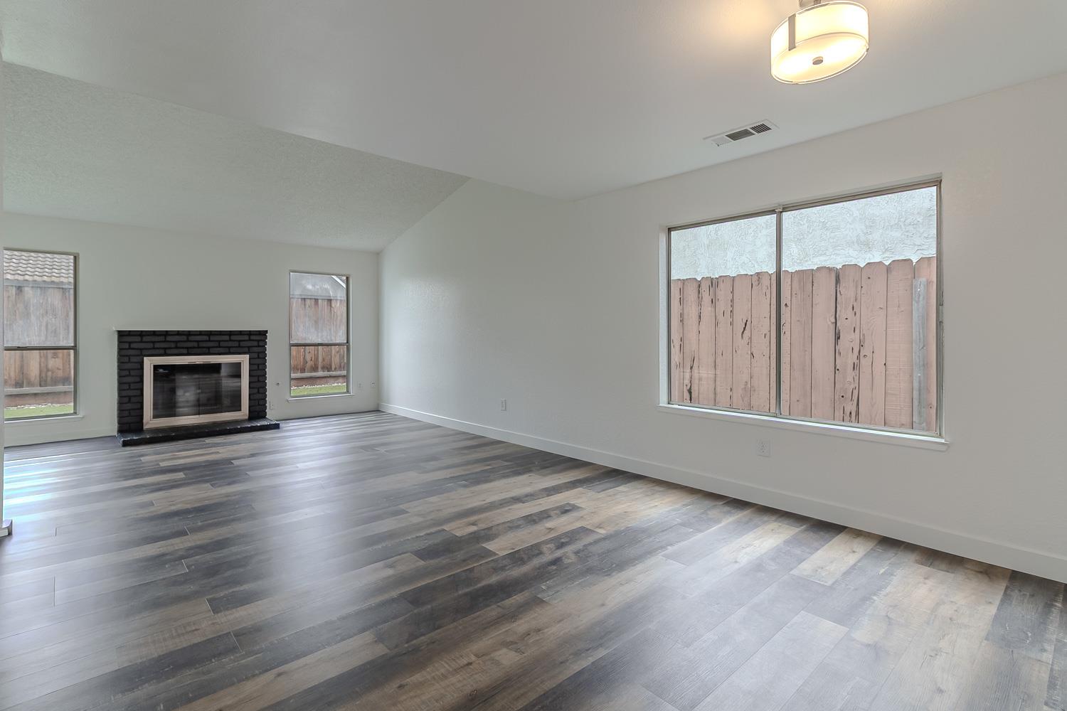 1128 Diablo Avenue Modesto, CA 95358 - Photo 6 of 23 an empty room with wooden floor fire place and windows