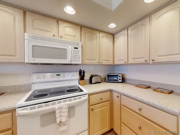 a kitchen with granite countertop white cabinets and white appliances