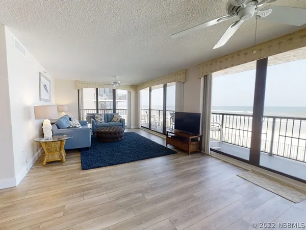a living room with furniture a large window and wooden floor
