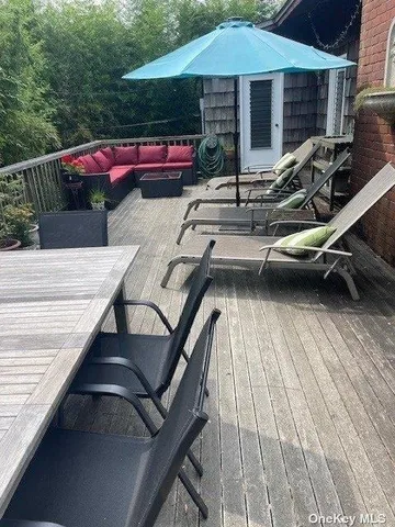 a view of a roof deck with table and chairs under an umbrella with wooden floor
