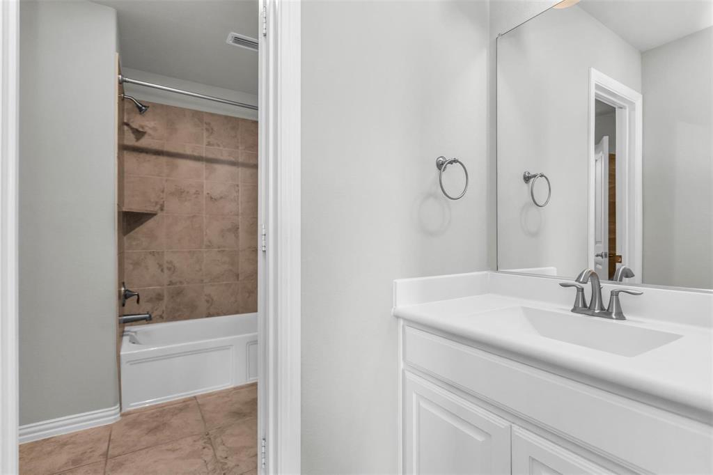 6333 Hall Road Frisco, TX 75034 - Photo 29 of 38 White vanity with integrated sink, brushed nickel faucet, large wall mirror, and tile flooring