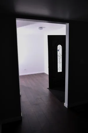 a view of an empty room with wooden floor and entryway
