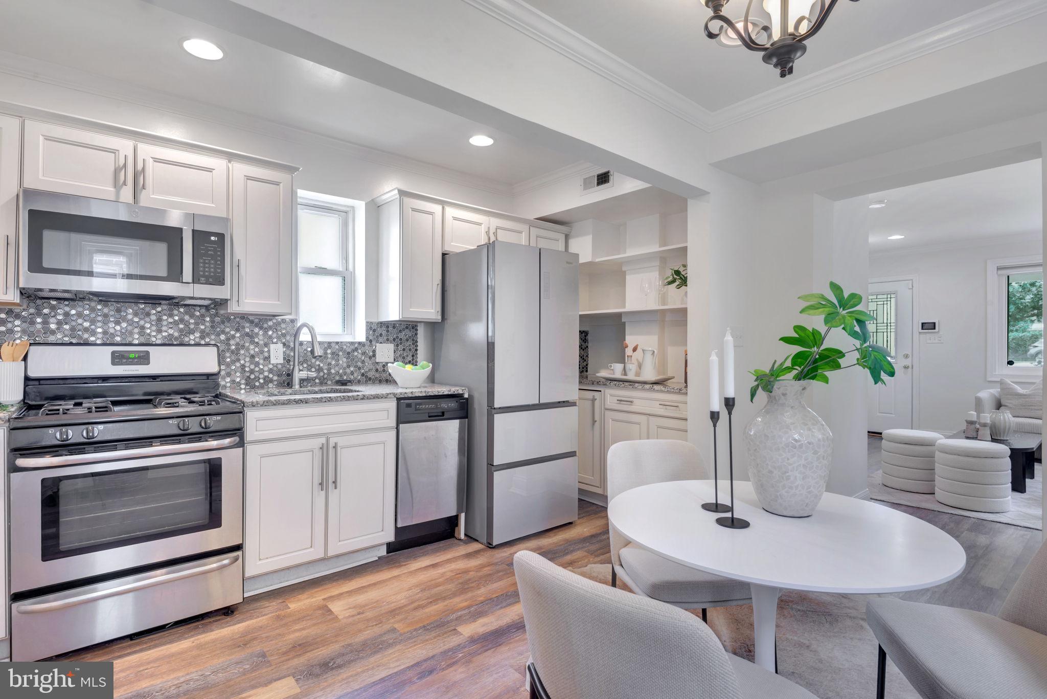 2842 30th Street Northeast Washington, DC 20018 - Photo 7 of 18 a kitchen with stainless steel appliances granite countertop a stove a sink dishwasher a refrigerator and a dining table with wooden floor