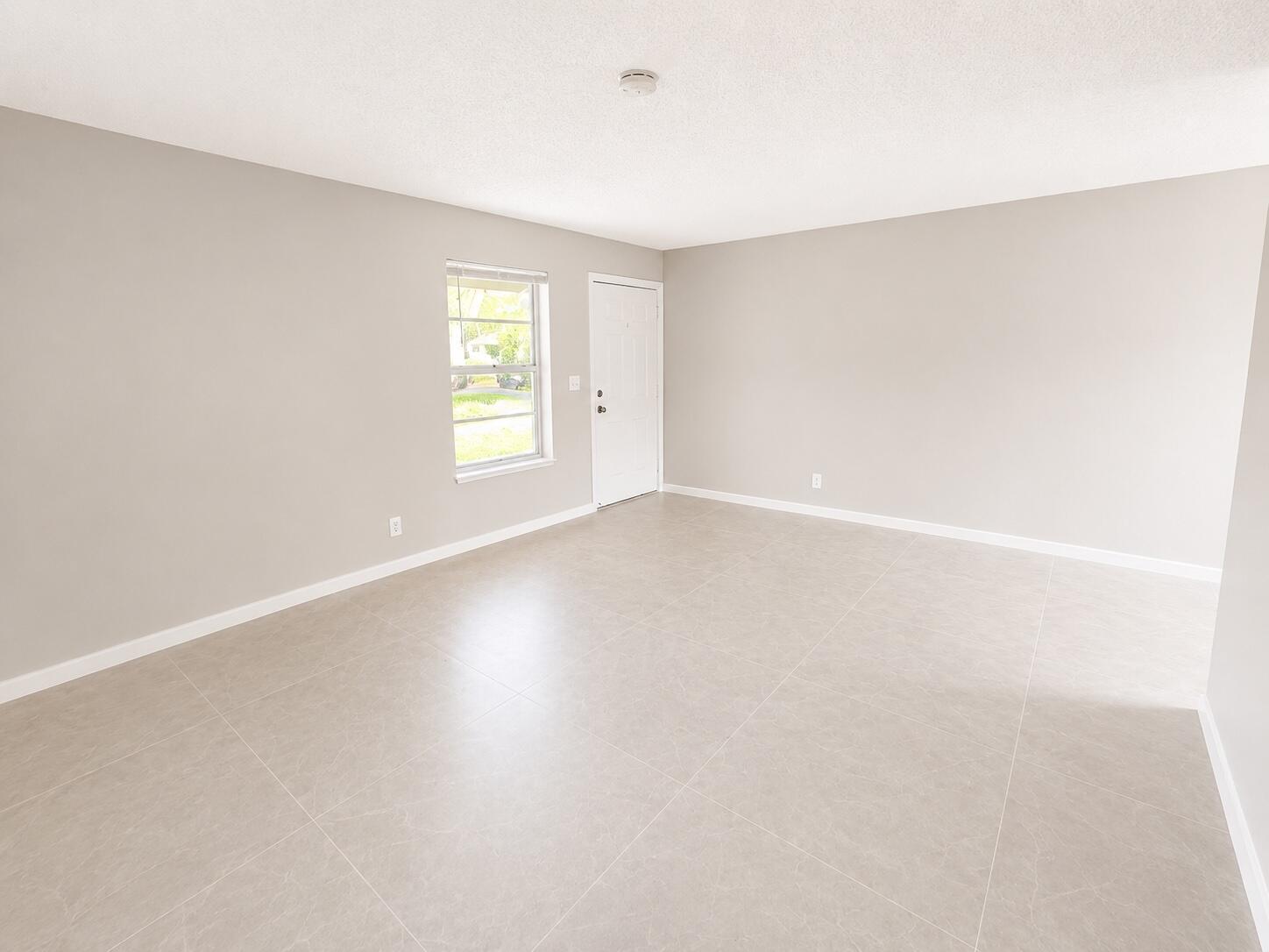 1794 Juno Road, Unit 2 North Palm Beach, FL 33408 - Photo 3 of 9 a view of an empty room with wooden floor and window