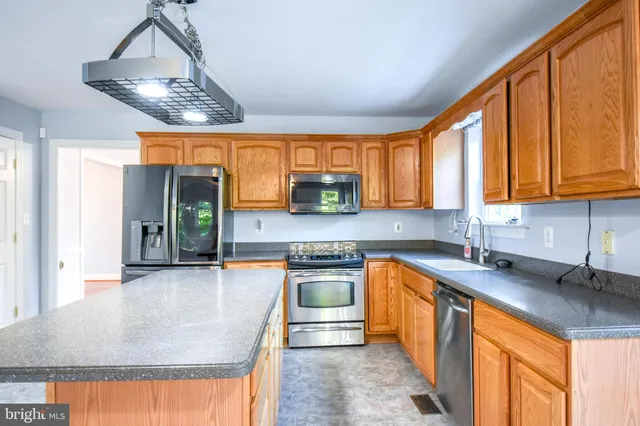 a kitchen with stainless steel appliances granite countertop a sink window and cabinets