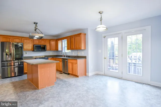 a large kitchen with stainless steel appliances granite countertop a stove a sink dishwasher a refrigerator and a fireplace with wooden floor