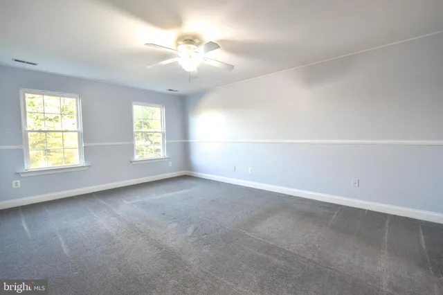 an empty room with windows and chandelier fan