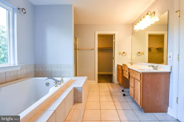 a spacious bathroom with a tub sink and mirror