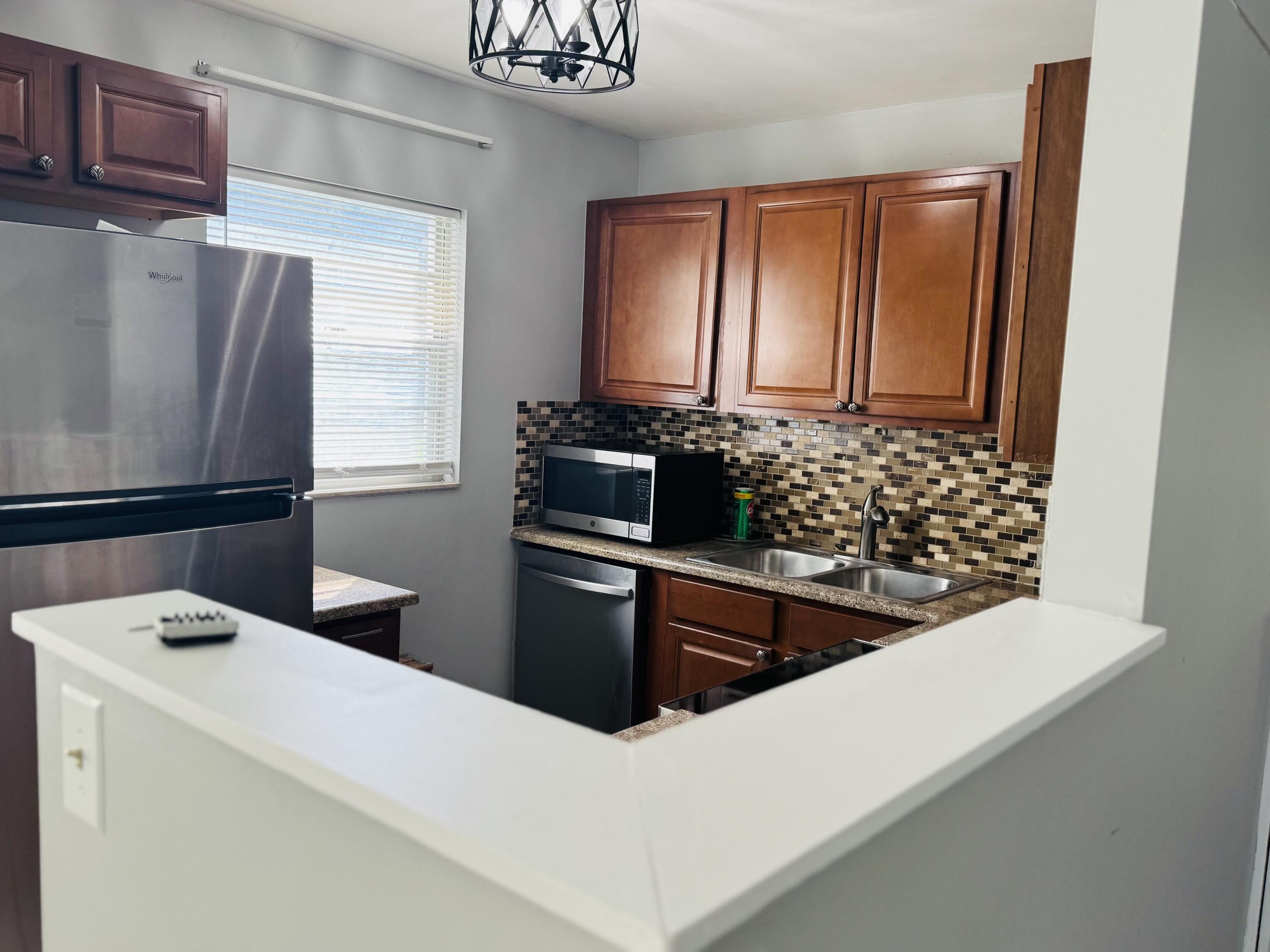151 Brighton Drive, Unit D Boca Raton, FL 33434 - Photo 26 of 29 a kitchen with stainless steel appliances a refrigerator and a stove