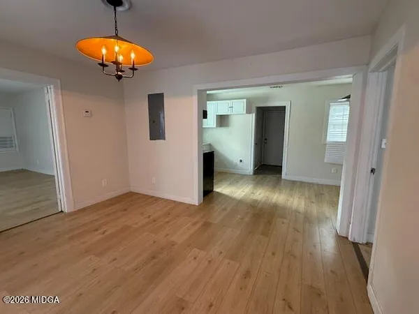 an empty room with wooden floor and chandelier