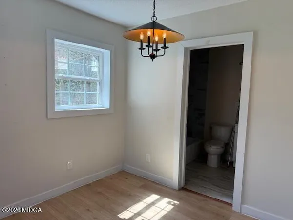 an empty room and a bathroom space with wooden floor