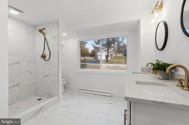 a bathroom with a granite countertop sink a mirror and shower