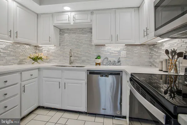 a kitchen with white cabinets and appliances