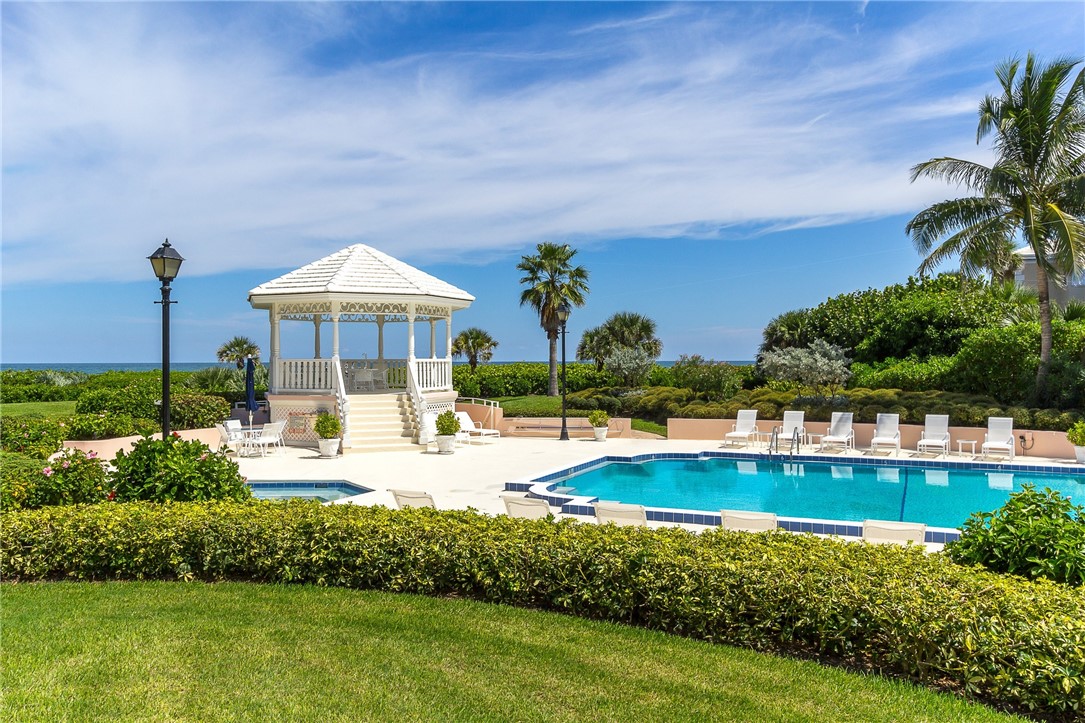 a view of a swimming pool with lawn chairs under an umbrella