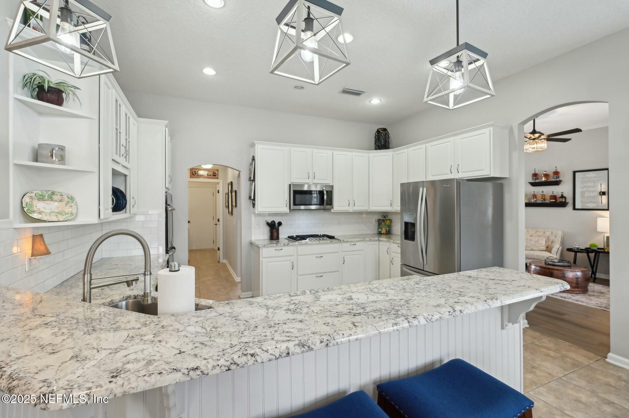1732 Margarets Walk Road Fleming Island, FL 32003 - Photo 9 of 55 a kitchen with stainless steel appliances kitchen island granite countertop a refrigerator a stove a sink and a dining table with wooden floor