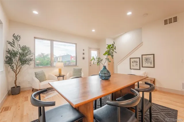 a dining room with stainless steel appliances kitchen island granite countertop a table chairs and a refrigerator