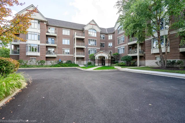 a front view of a residential apartment building with a yard and plants