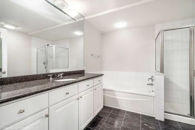 a bathroom with a granite countertop sink mirror and a bathtub