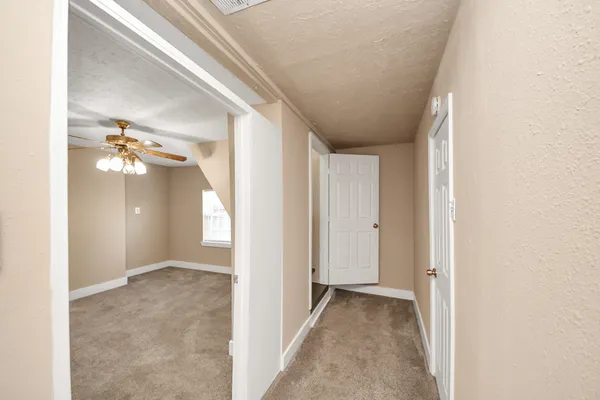 a view of an empty room with window and chandelier fan