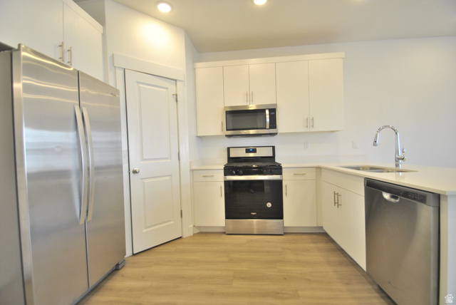 1219 West 1870 South Logan, UT 84321 - Photo 4 of 18 Kitchen with stainless steel appliances, light wood-style floors, a peninsula, recessed lighting, and white cabinets