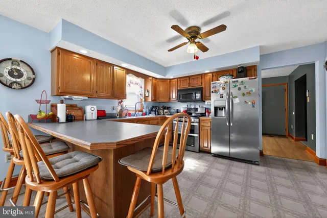 a kitchen with stainless steel appliances granite countertop a refrigerator a stove a sink a dining table and chairs with wooden floor