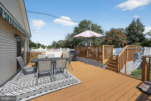 a view of a roof deck with table and chairs under an umbrella with wooden floor