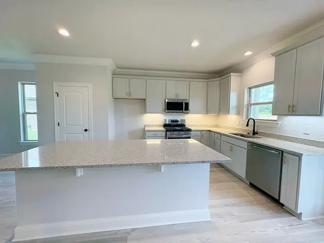 a kitchen with stainless steel appliances a sink a stove a refrigerator a center island and a window