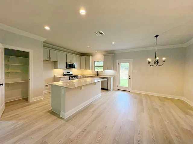 a kitchen with stainless steel appliances granite countertop a sink a stove a refrigerator and island with wooden floor