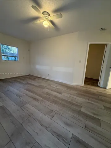 an empty room with wooden floor and fan