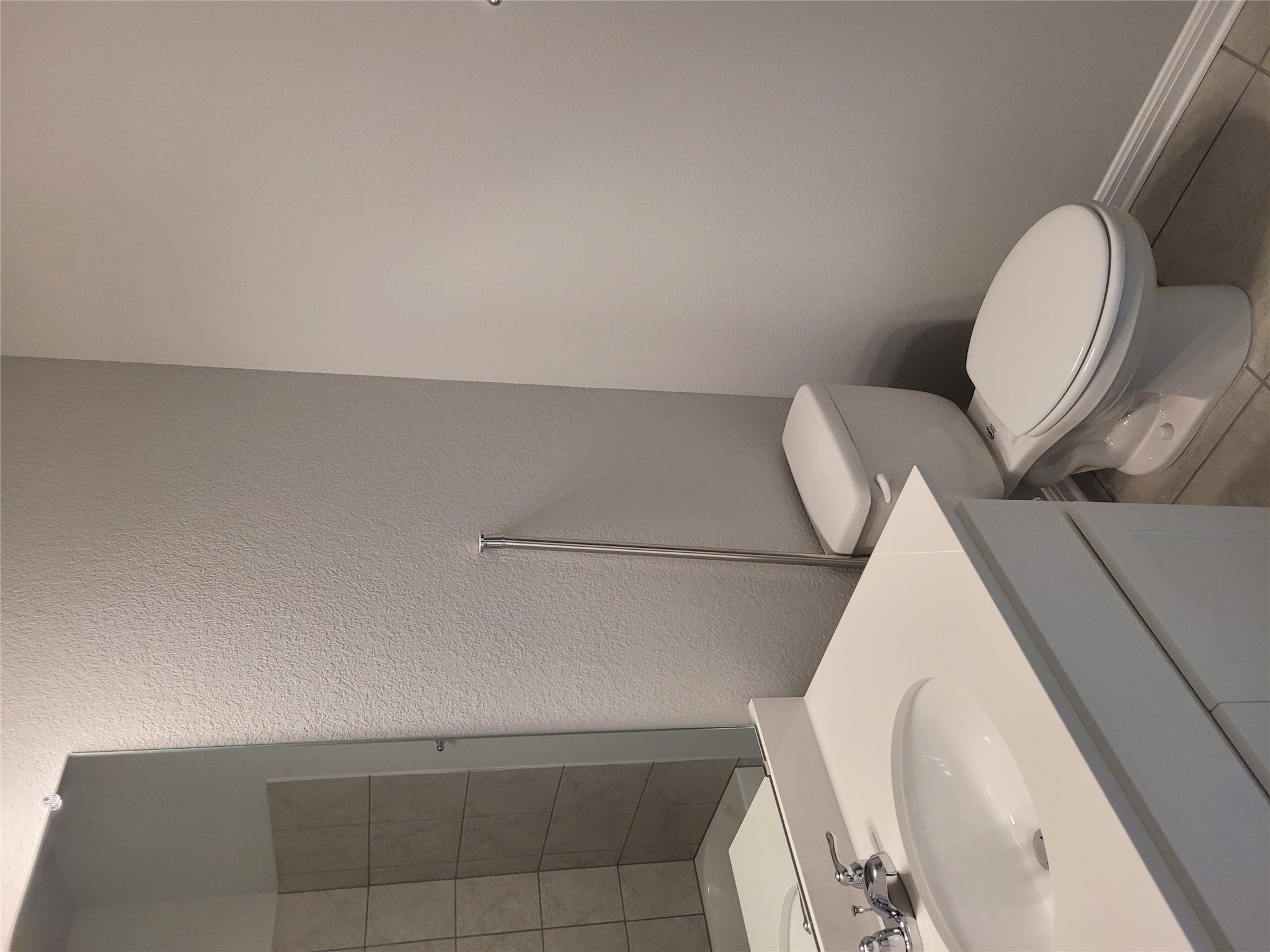 131 Wild Wind Cove Jarrell, TX 76537 - Photo 4 of 26 Bathroom featuring a white vanity with an integrated sink and chrome faucet, a wall-mounted mirror, a white toilet, and light-toned tile flooring