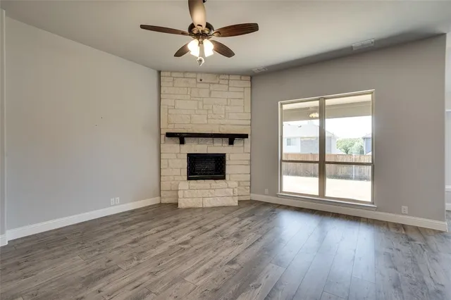 an empty room with wooden floor fan and windows