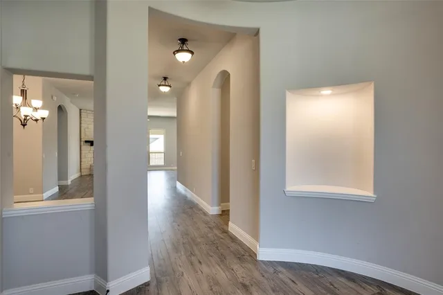 a view of a hallway with wooden floor and a bathroom