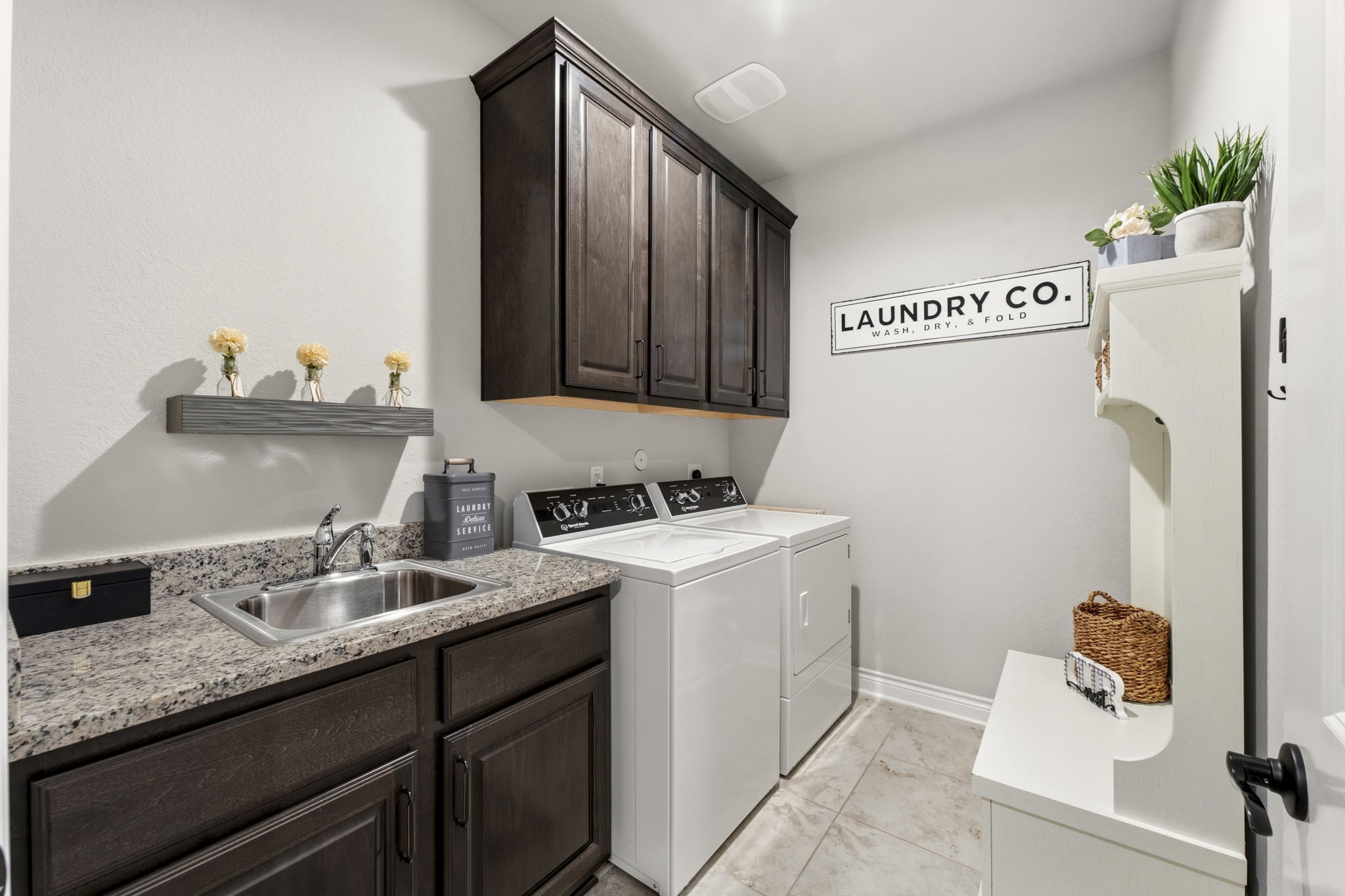 14012 Beartooth Bend Trail Conroe, TX 77384 - Photo 27 of 50 Designed with both style and efficiency in mind, the laundry room features tile flooring and both upper and lower cabinetry for optimal organization. A convenient utility sink with granite countertop enhances functionality.