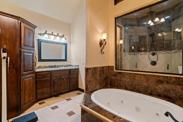 a bathroom with a bathtub mirror and sink