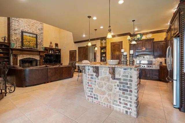 a view of a kitchen with kitchen island granite countertop a refrigerator a stove a sink a dining table and chairs with wooden floor